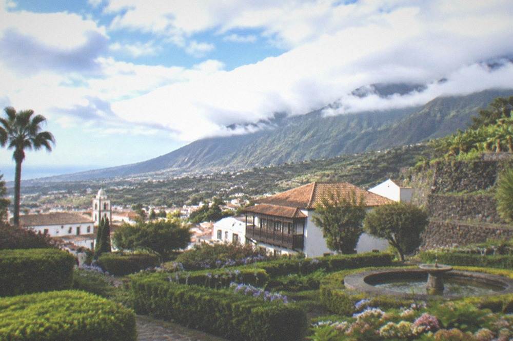 A garden with trimmed hedges and flowers in La Orotava with the Orotava valley behind