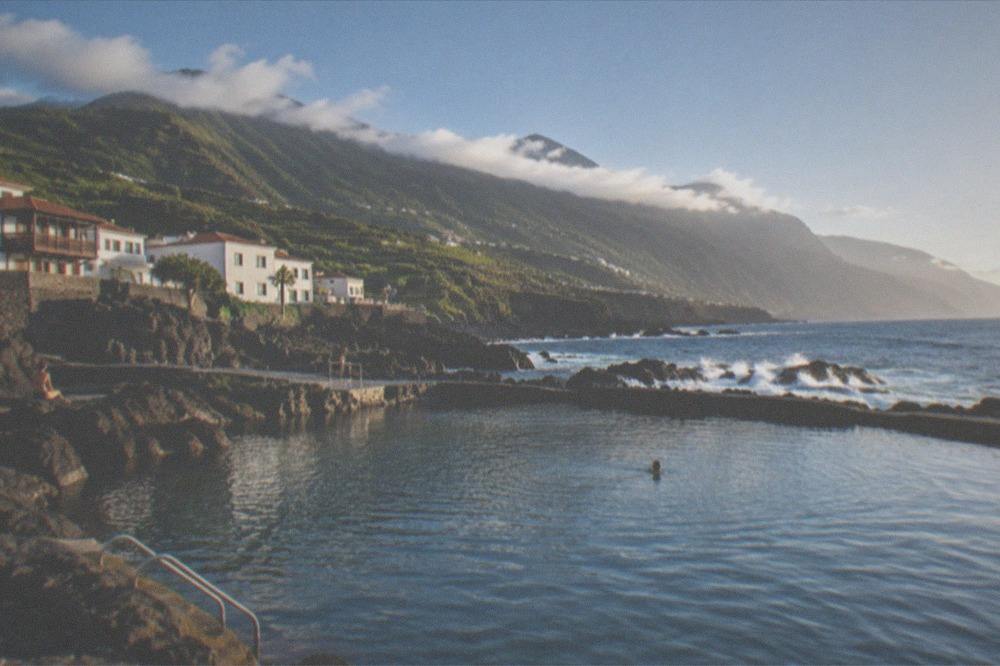 Sunlight over a calm natural pool with hills of northern Tenerife in the background