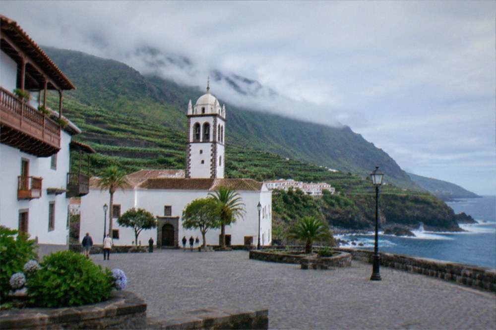A cobbled square in Garachico with old whitewashed buildings and a church tower