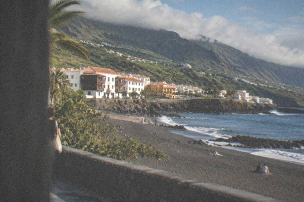 Seafront promenade and dark sand beach in Puerto de la Cruz under afternoon light