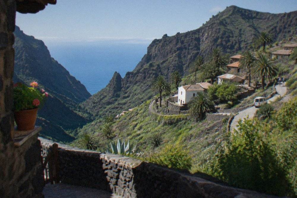 A small stone village of terraced houses sitting on a ridge above a deep green ravine in western Tenerife