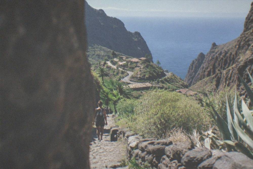 A rocky ravine path descending between high stone walls towards the sea in the distance