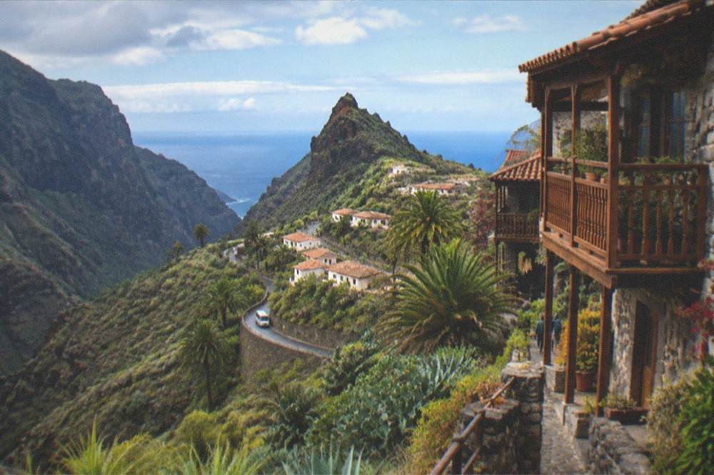 Terraced stone houses with wooden balconies overlooking a deep green valley