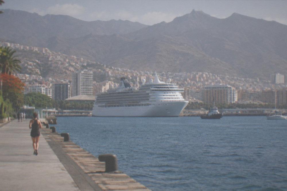 A cruise ship at anchor in the port of Santa Cruz de Tenerife with the city rising behind it