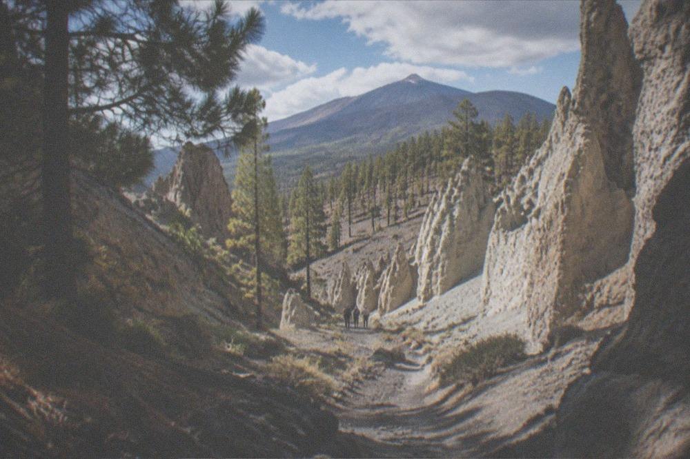 Tall pale ash towers and ravines on either side of a faint path under strong sunlight