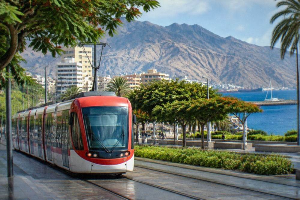 A red and white tram travelling along a city street in Santa Cruz de Tenerife