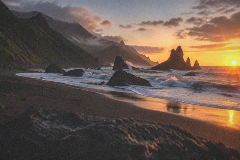 Sunset light over the Atlantic with silhouetted rocks on a wild Tenerife beach