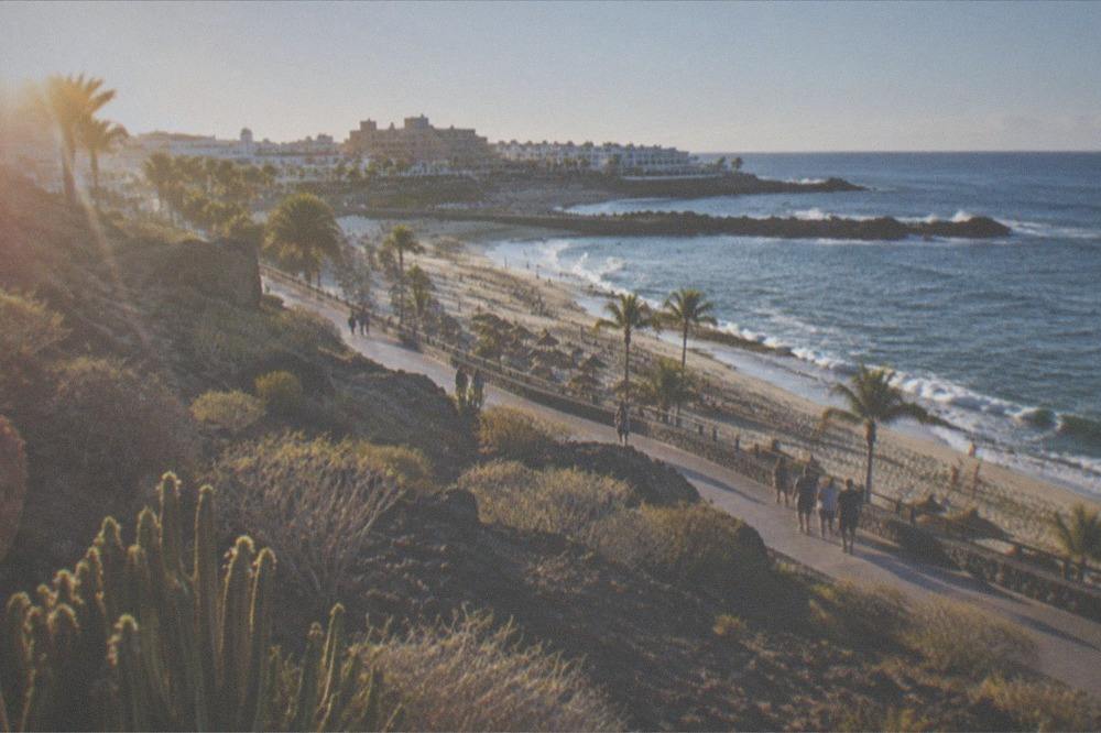 A coastal walkway linking resort beaches with parasols and palm trees