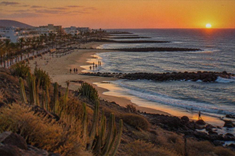 Golden beach at sunset with breakwaters silhouetted against an orange sky