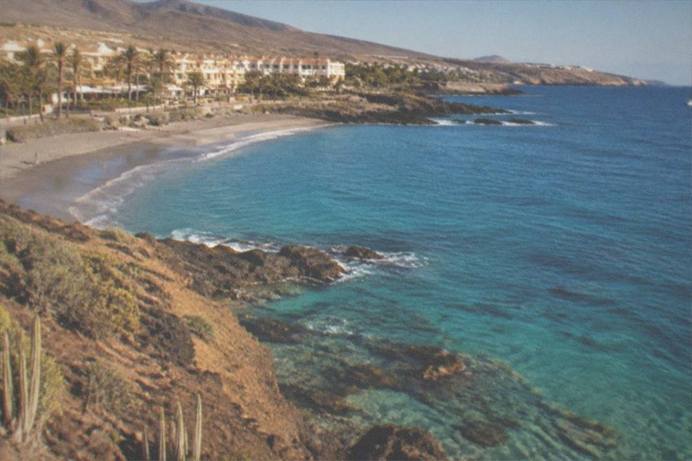 Clear turquoise water over pale rocks seen from a beach edge
