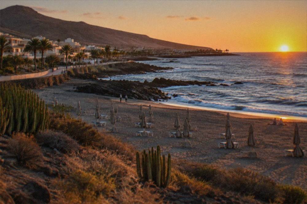A resort beach at sunset with parasols folded and calm sea beyond