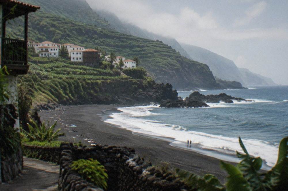 A wide black sand beach beneath a dark cliff on the north coast of Tenerife