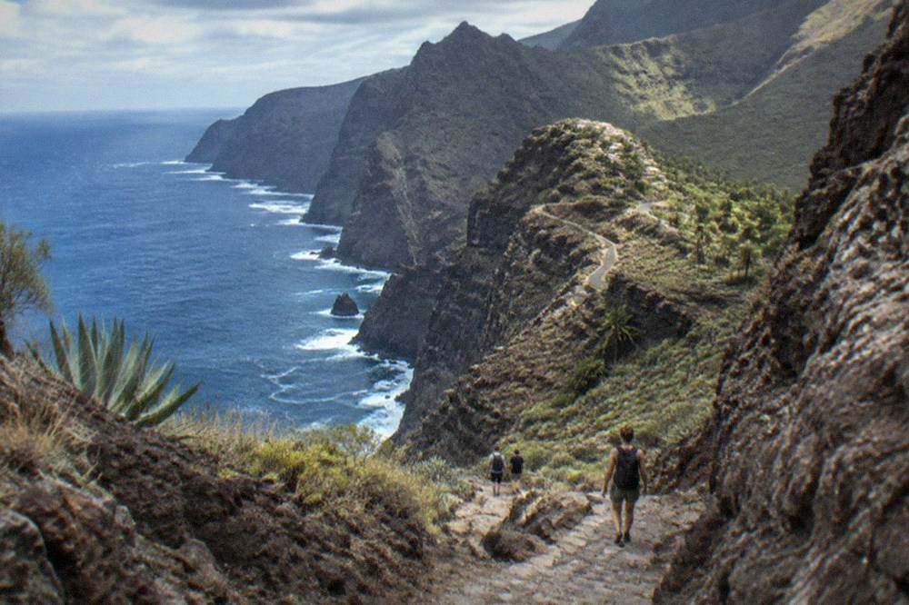 A narrow rocky gorge path descending between steep stone walls towards the sea