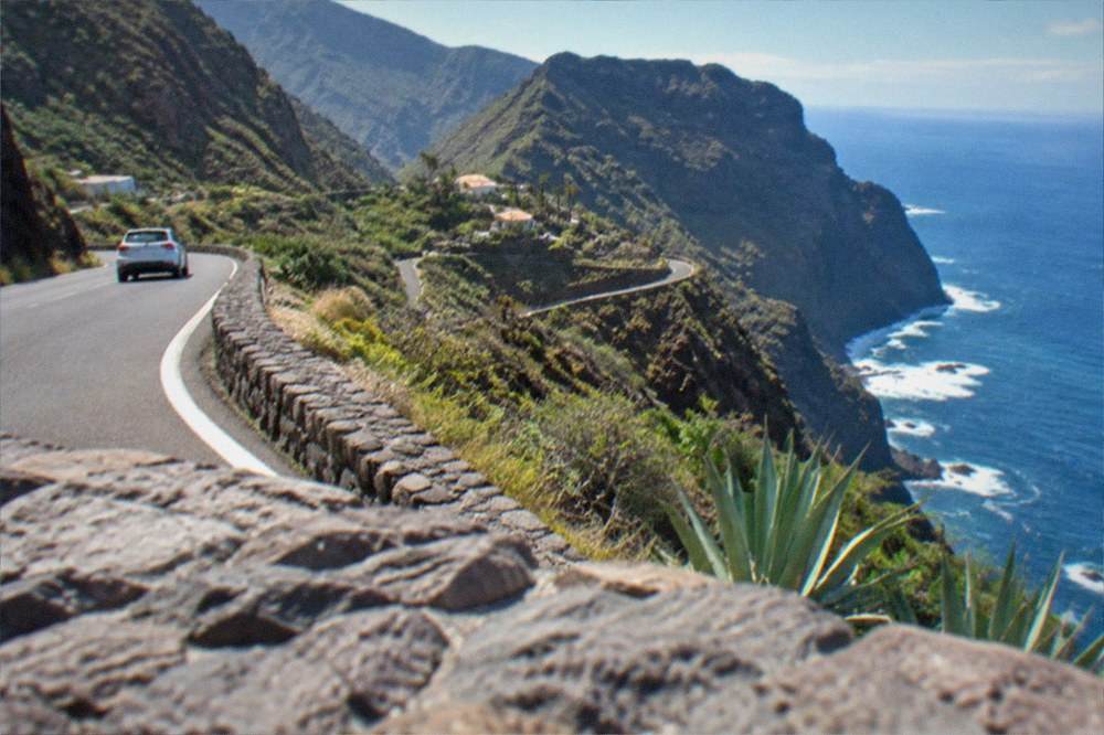 A coastal road winding between hills with the ocean visible in the distance