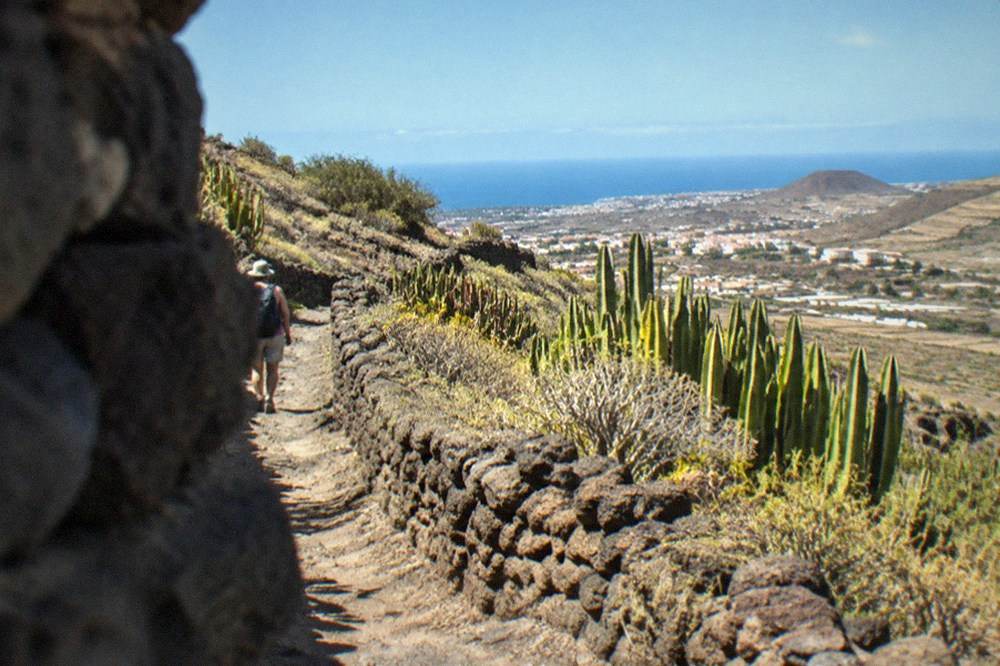 A path leading between stone terraces with the town of Güímar below