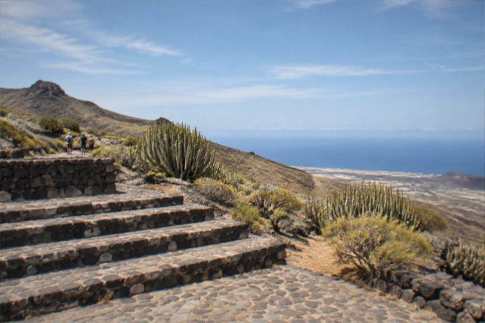 Sunlight over terraced stone steps with the Atlantic in the distance