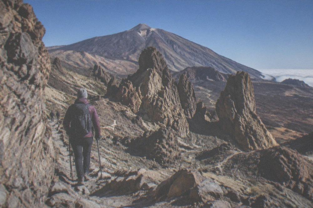 A hiker in warm clothing walking a stony trail among rock towers on a cold clear morning