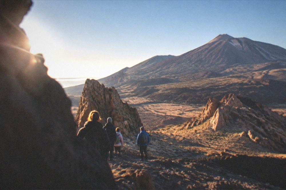 A small group with a guide standing among volcanic rocks in Teide National Park