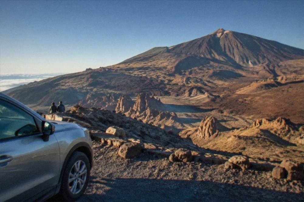 A car parked beside a road at a viewpoint overlooking the volcanic caldera of Teide National Park