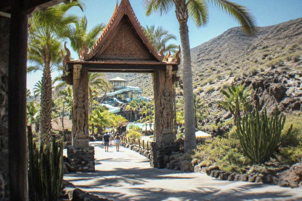 Palm trees and a Thai-style carved gate at the entrance to a water park in Tenerife