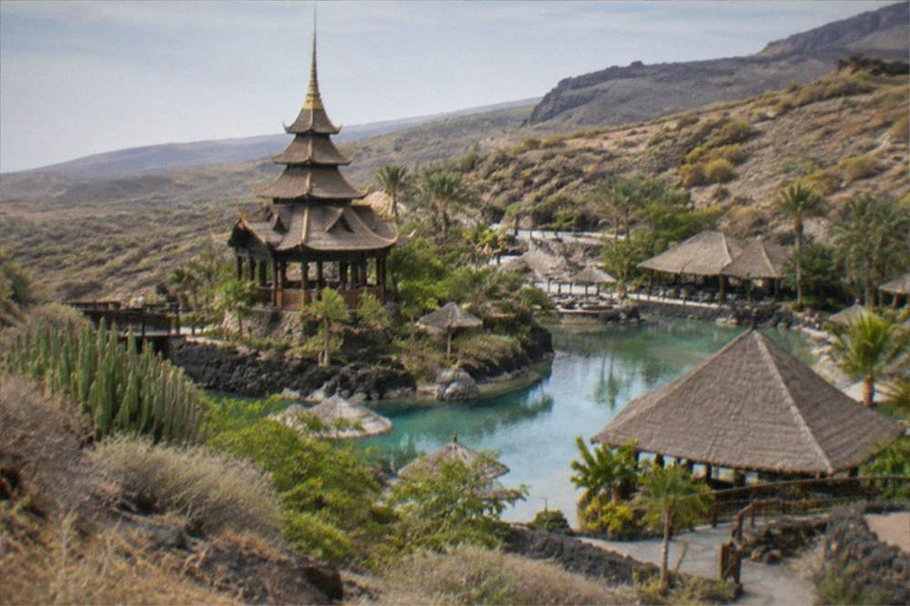 A Thai-inspired ornamental tower and thatched roofs above a swimming lagoon