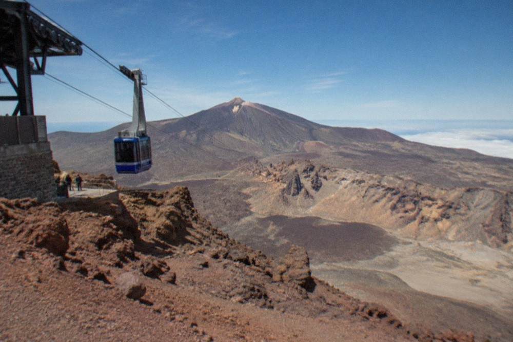 The upper cable car station buildings on a reddish volcanic ridge