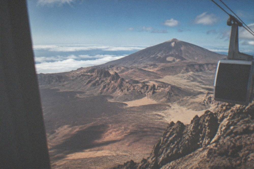 A wide view from a high volcanic ridge over layered lava fields and distant clouds