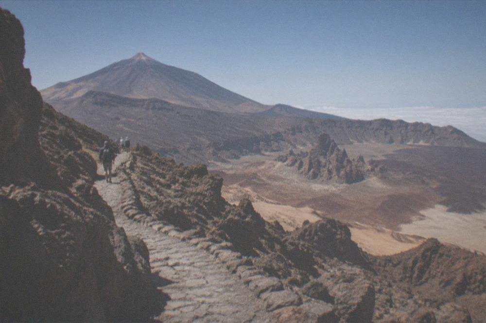 A stone trail winding between dark volcanic rocks near a crater rim