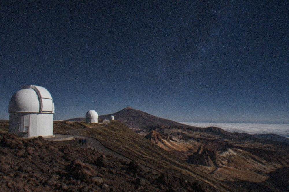 White telescope domes of the Teide Observatory standing on the Izaña ridge under a clear blue sky