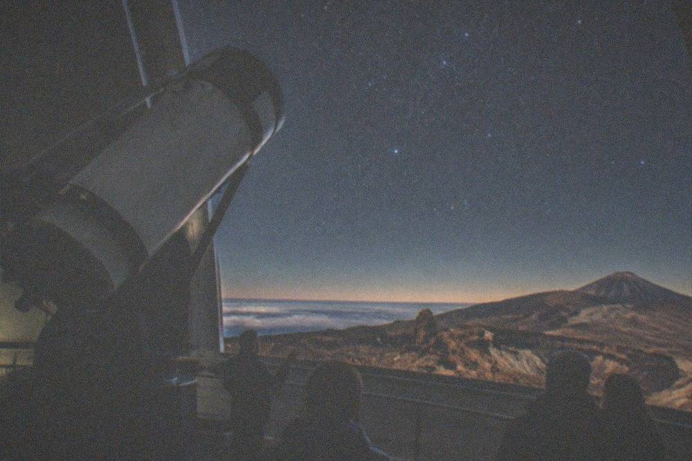 The interior of an observatory building with a solar telescope and a guide explaining instruments to visitors