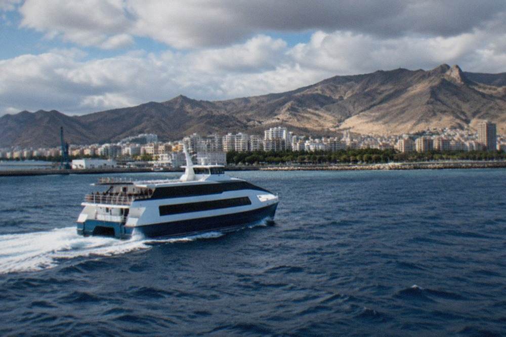 A fast ferry leaving Santa Cruz de Tenerife harbour with the Tenerife coastline behind it