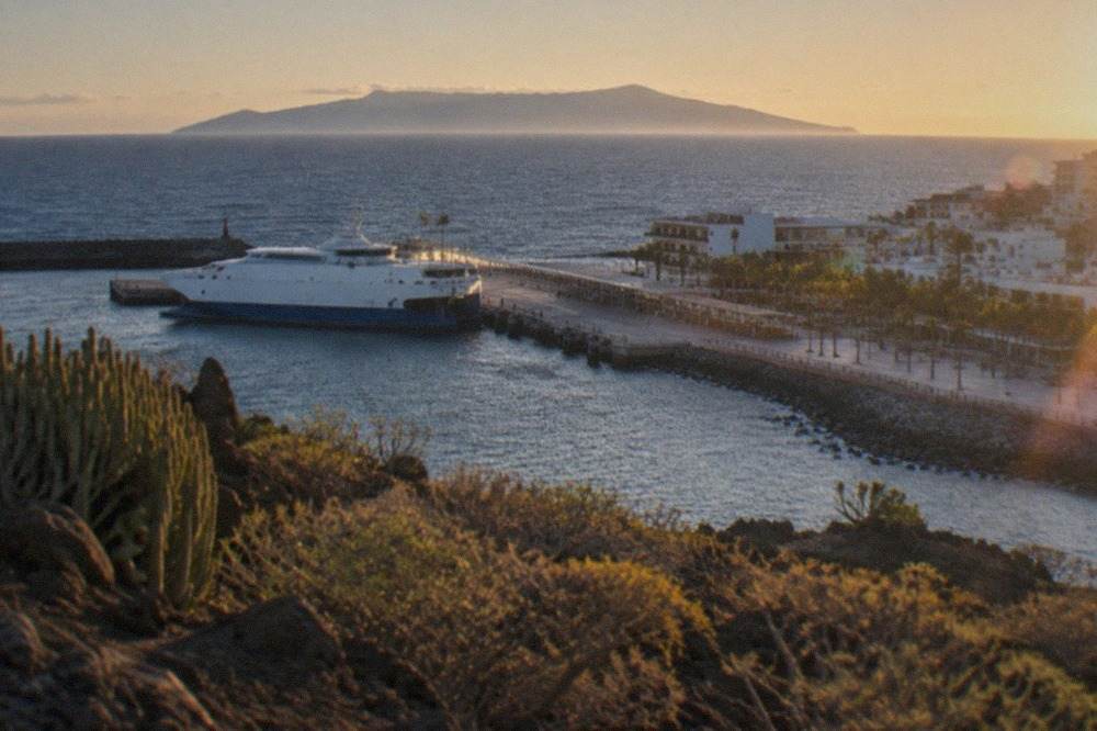 Ferry at the port of Los Cristianos with La Gomera visible on the horizon across the sea