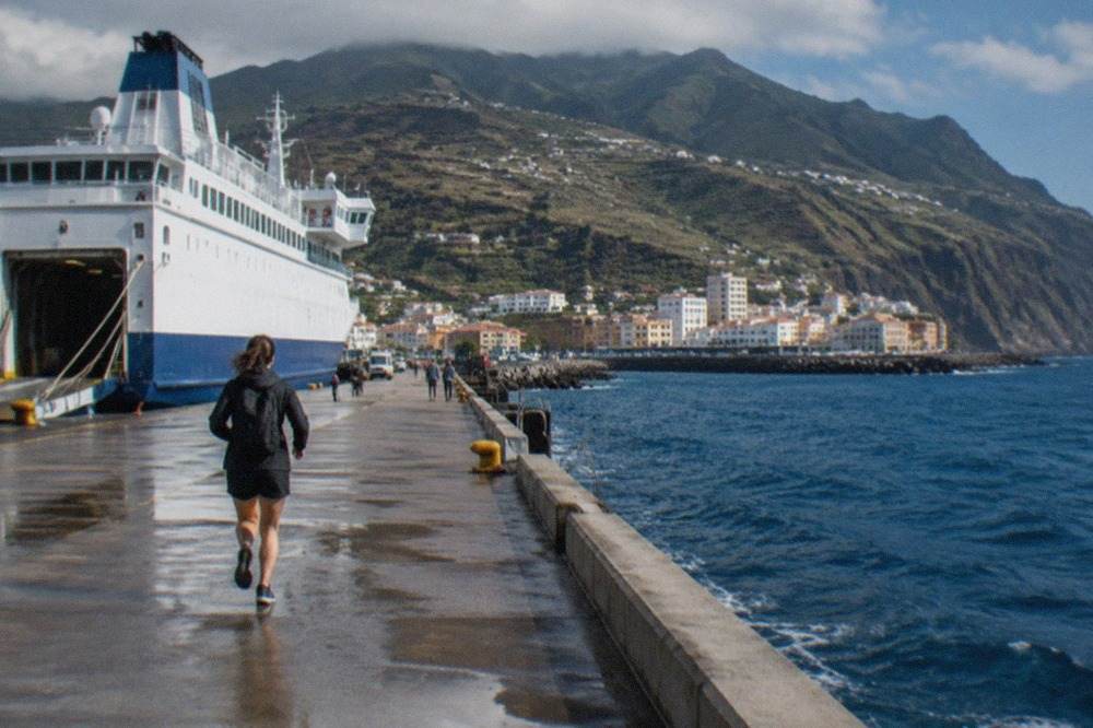 A large ferry docked at a Canary Islands port with hills behind it