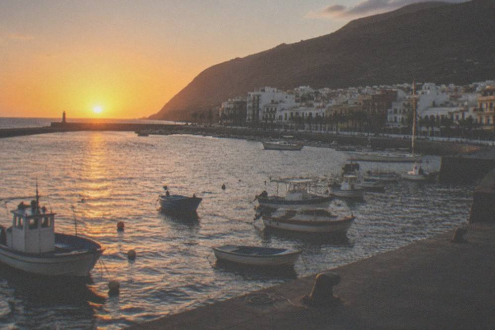 A quiet Canary harbour at sunset with small boats moored along the quay
