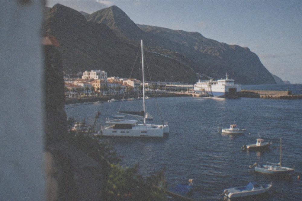 A catamaran and small boats in a harbour with a ferry at the far quay
