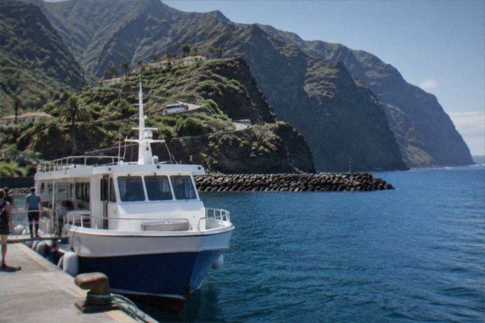 A ferry at a harbour with green mountainous island coastline in the distance