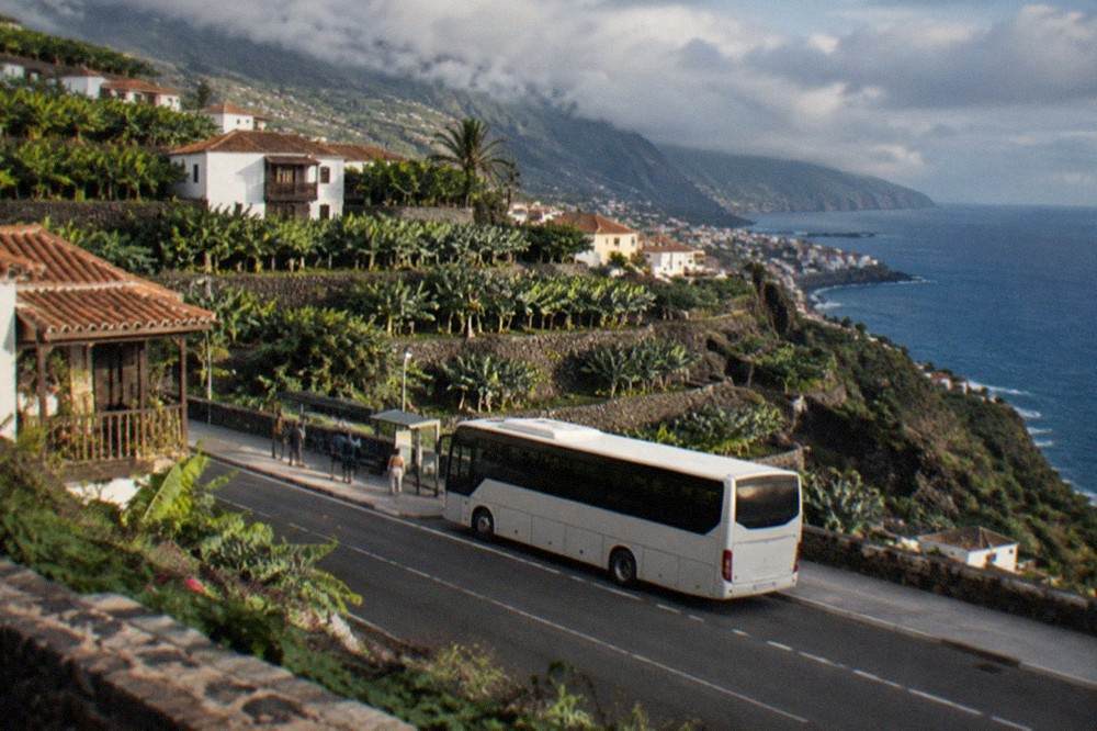 An island bus at a stop on a Tenerife road with hills behind