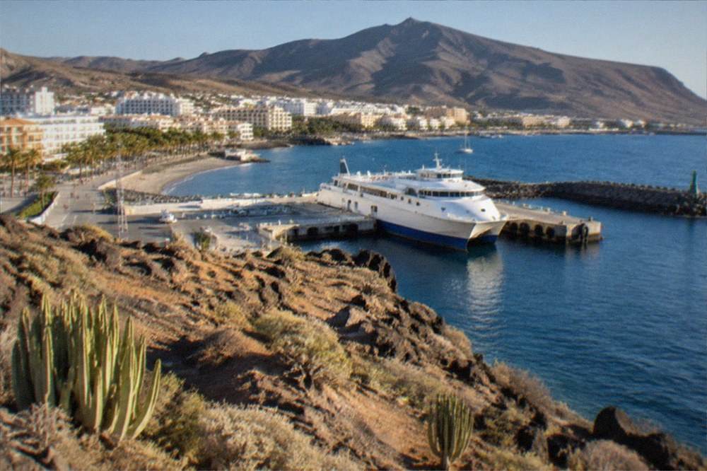 A ferry at the harbour in Los Cristianos with hills behind