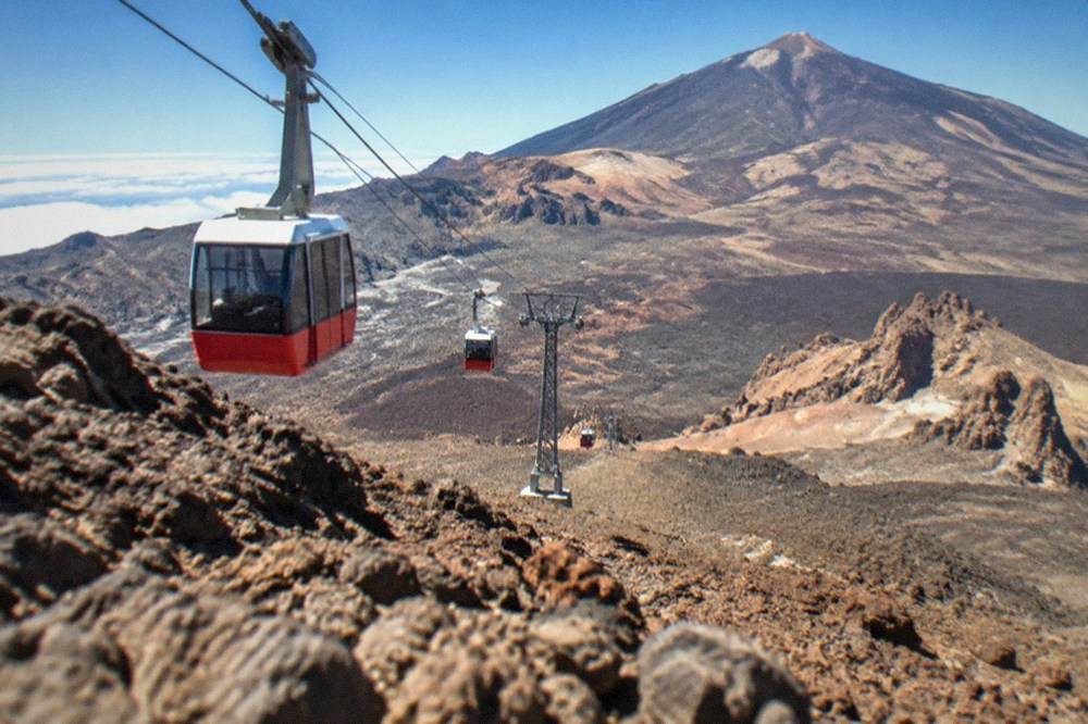 The red and white cable car cabins travelling up the steep slope to La Rambleta station
