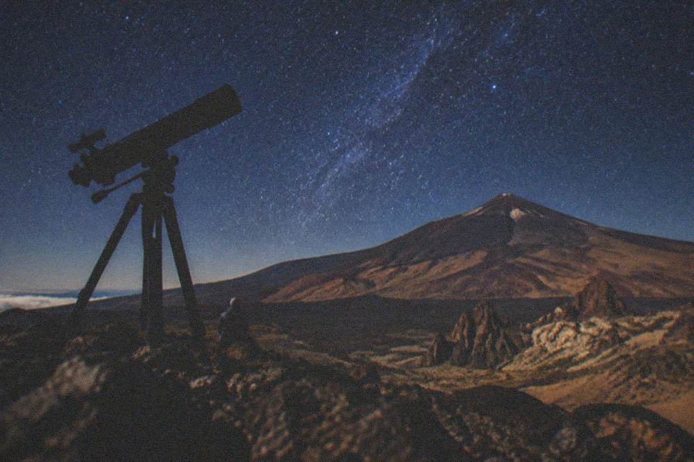 Telescope silhouetted against a star-filled sky above Teide National Park