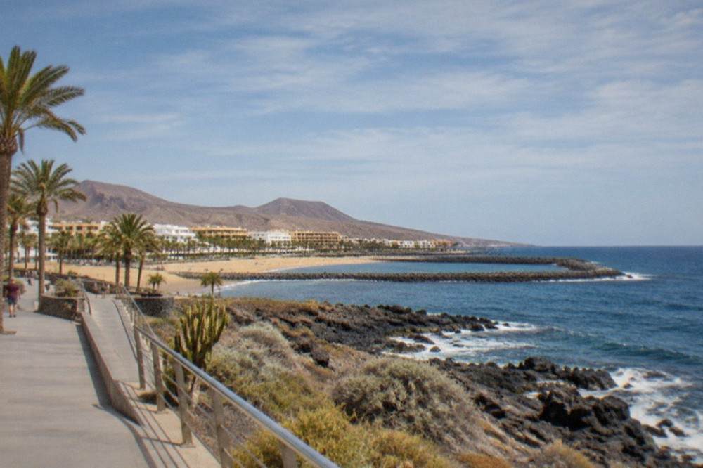 A level seafront walkway in a southern Tenerife resort with ramps and palm trees