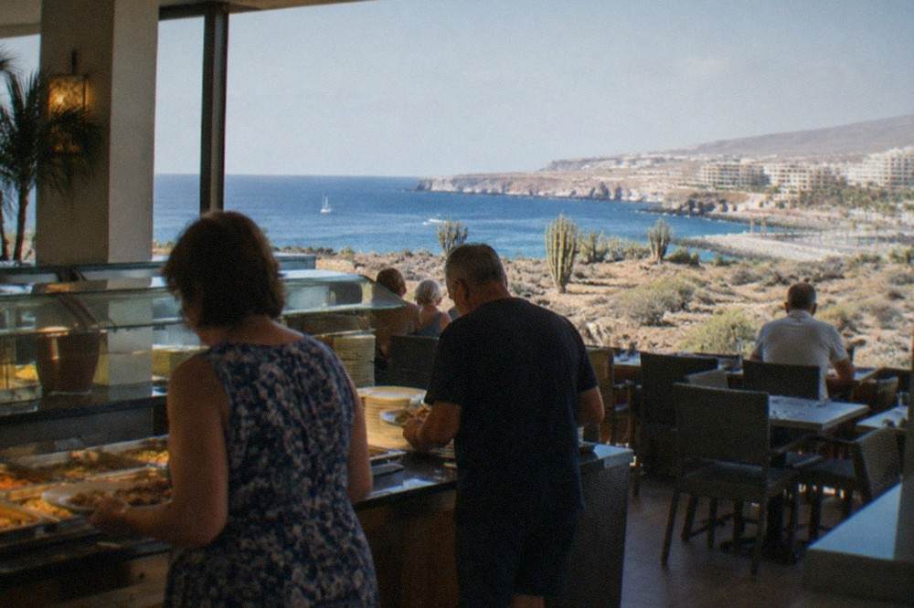 A buffet restaurant interior with trays of hot food and diners holding plates