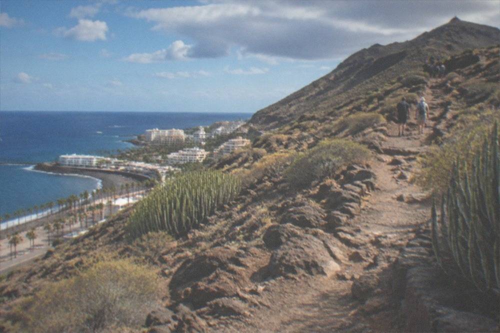A signposted hiking trail rising through volcanic rock toward a mountain summit