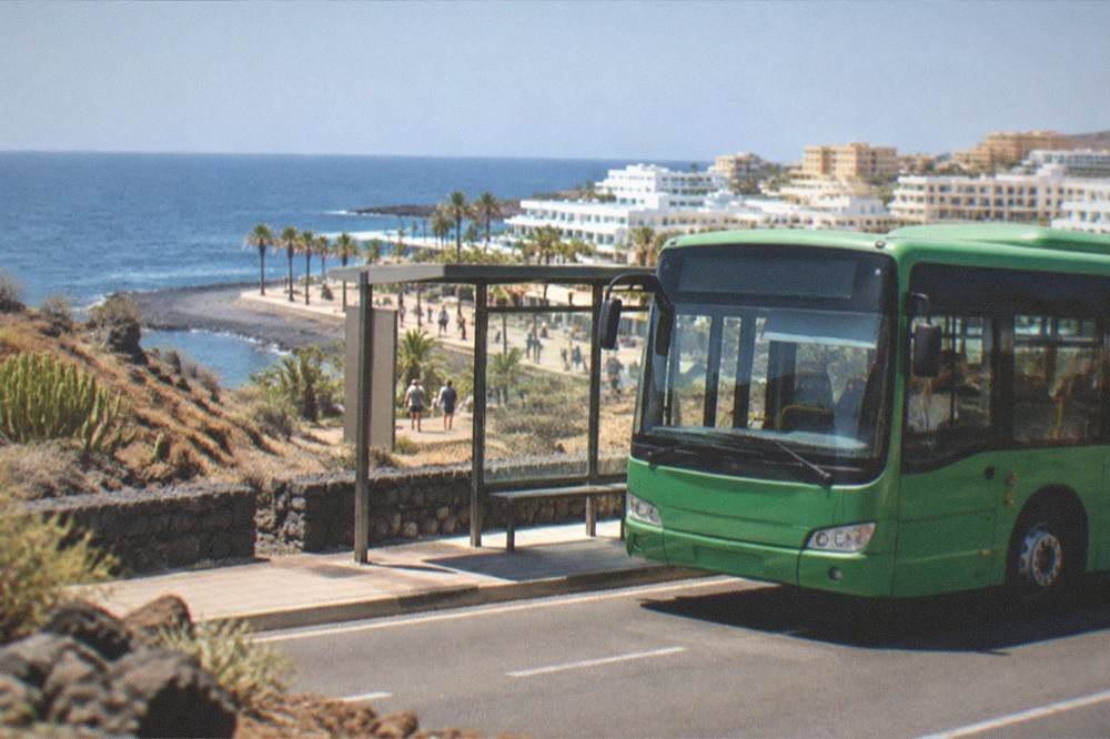 A green island bus at a roadside stop on a coastal road