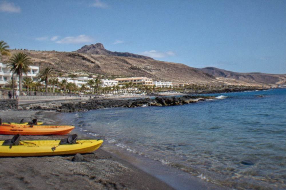 Kayaks pulled up on a beach with clear shallow water