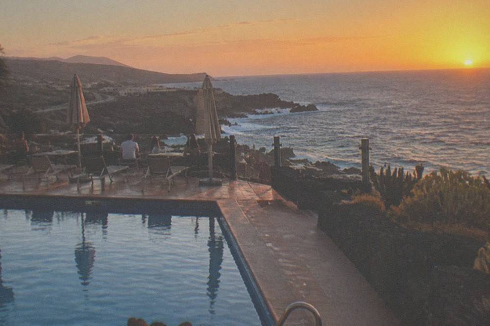 A hotel pool terrace overlooking the sea at sunset