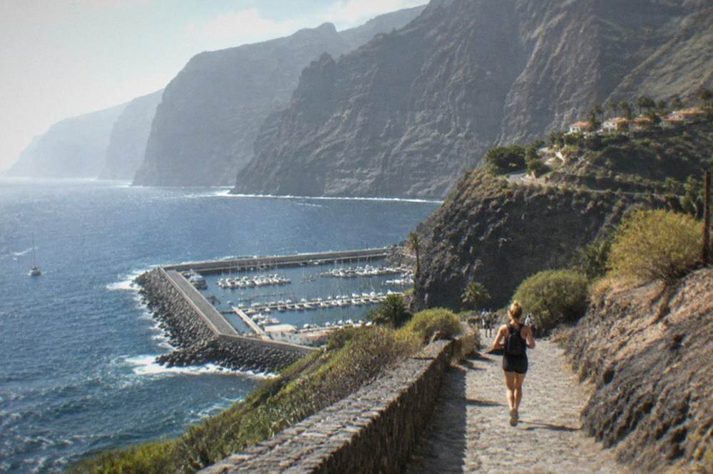 Dark volcanic cliffs of Los Gigantes rising above a small marina