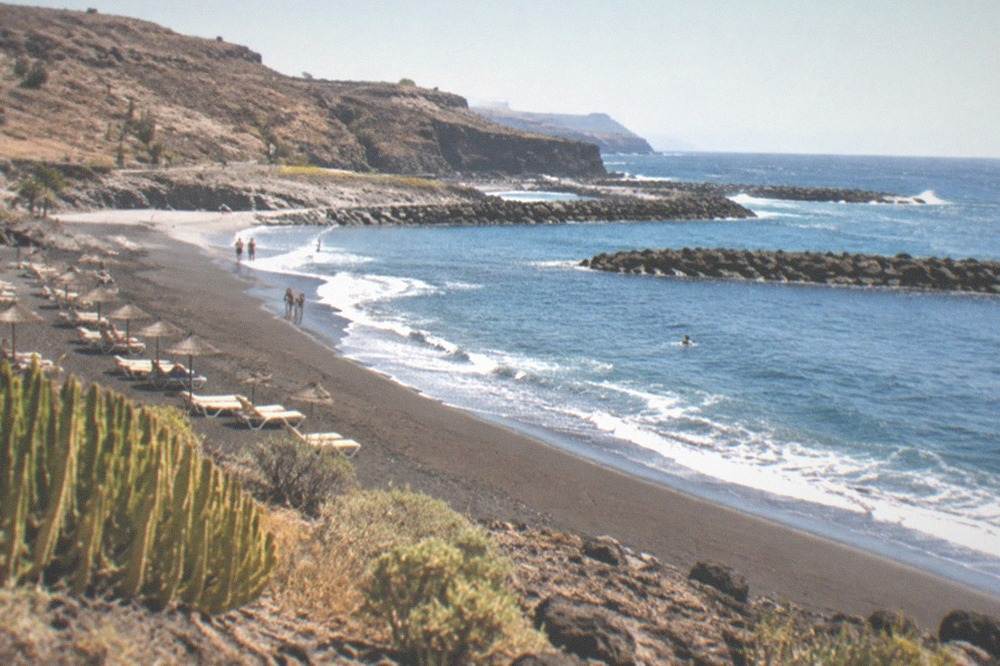 Golden sand beach with breakwaters and sun loungers under a clear sky