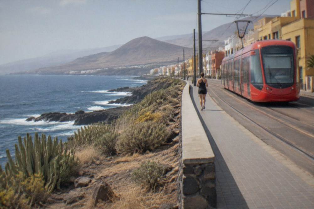 A red tram passing colourful buildings in a Canary Islands town