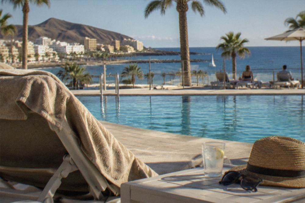 A hotel pool terrace with sun loungers and palm trees in a Tenerife resort